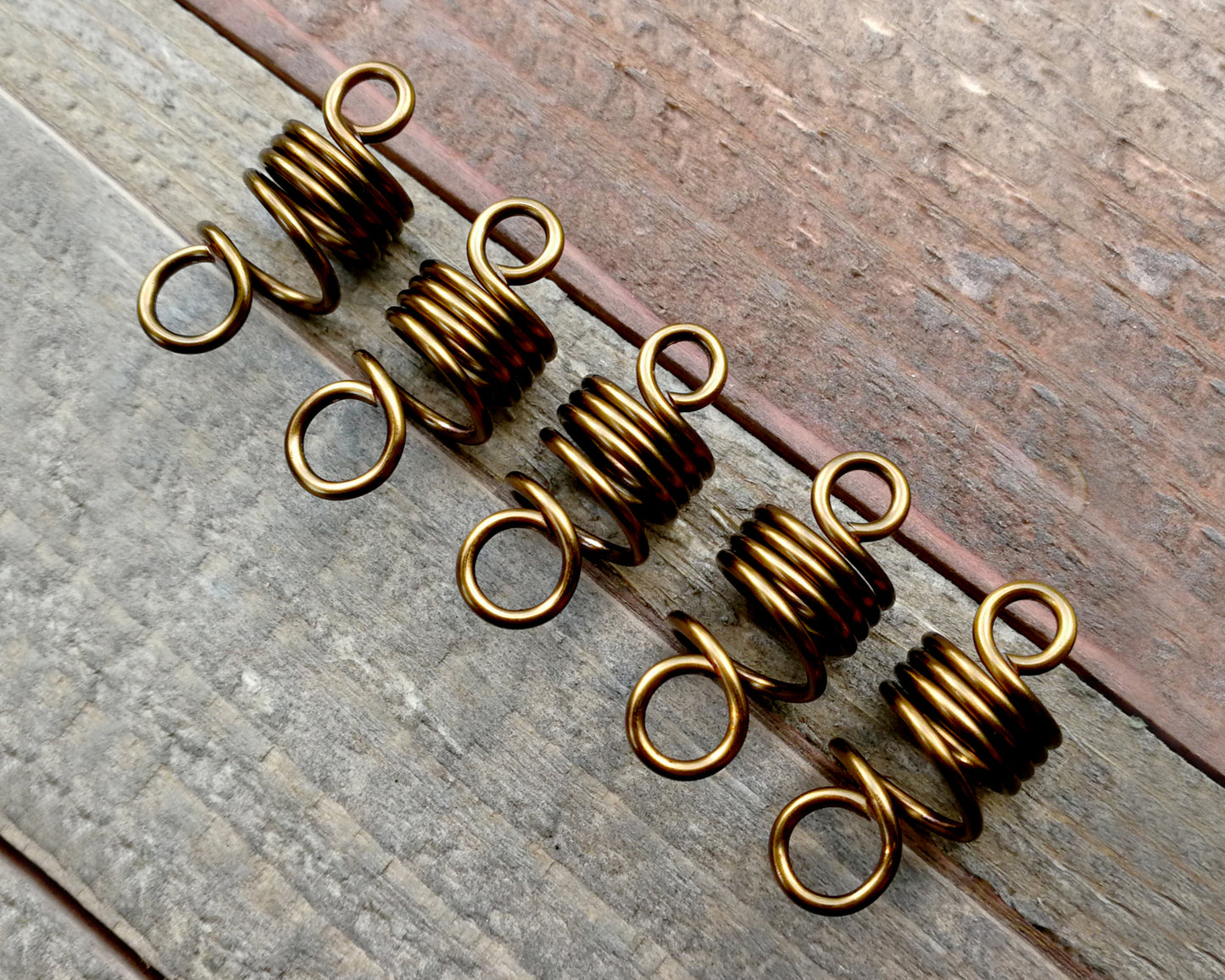 Set of 5 filigree beads on wood background.