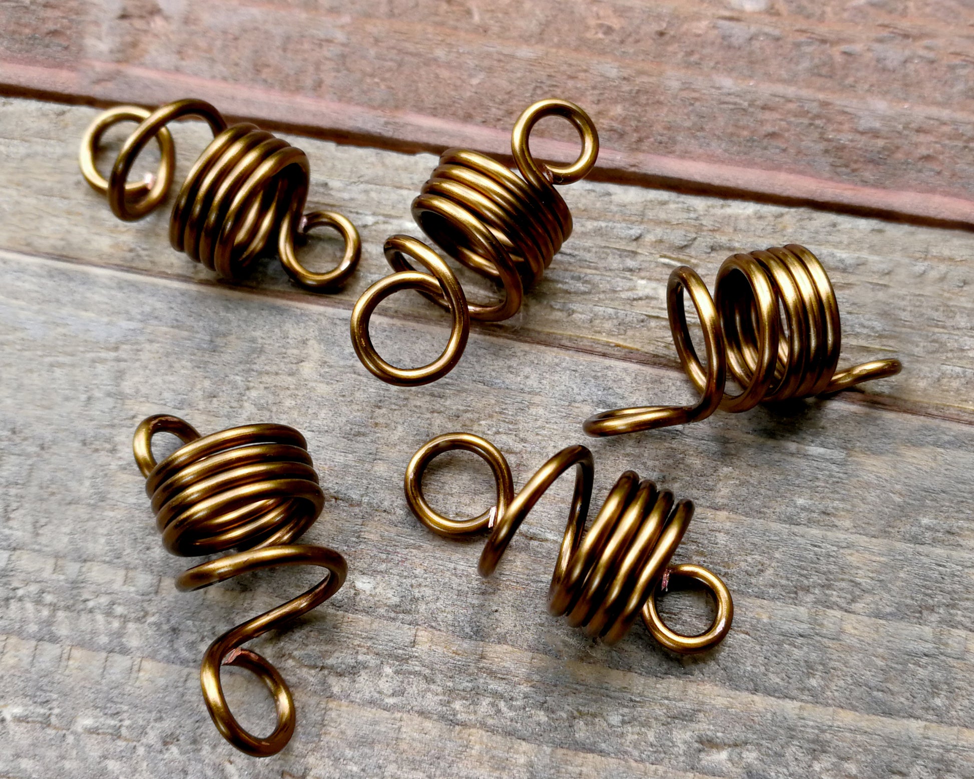 Set of 5 filigree beads on wood background.