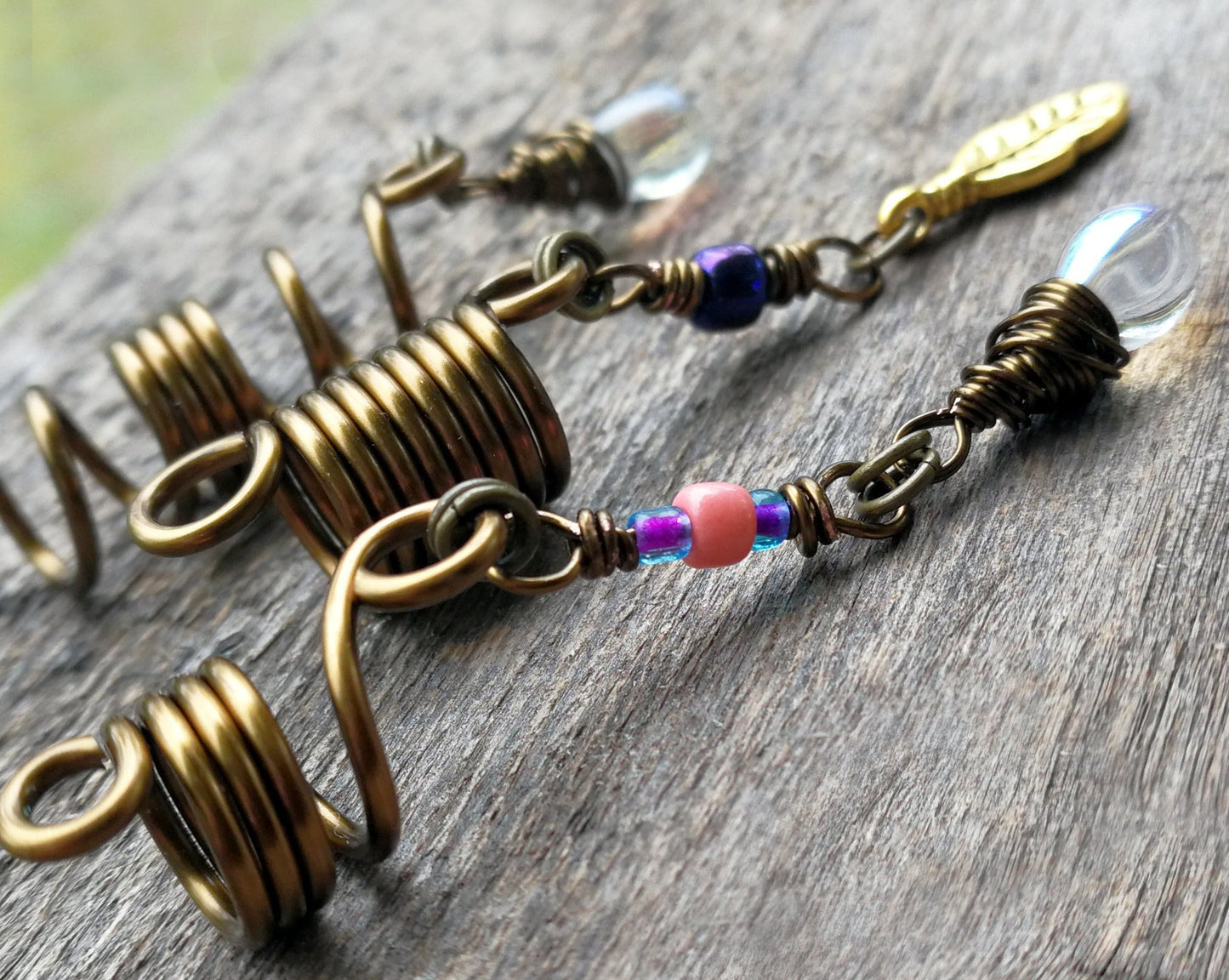 Set of 3 fall color dread beads on wood background, side view.