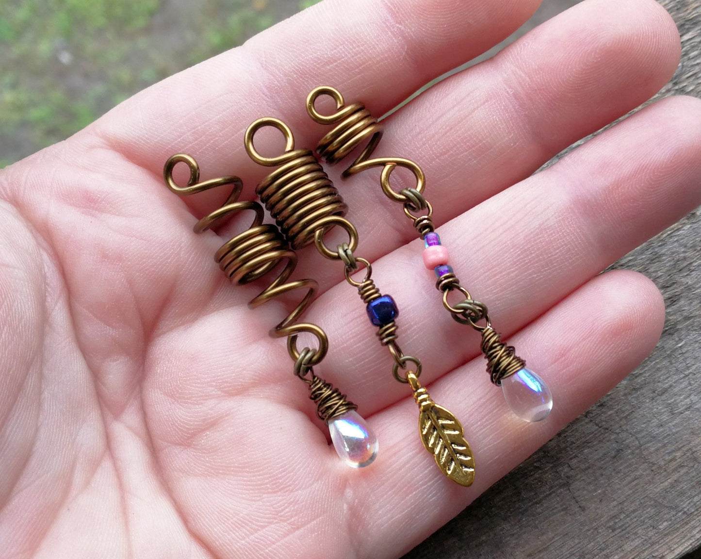 Set of 3 fall color dread beads on wood background displayed in hand to show scale.