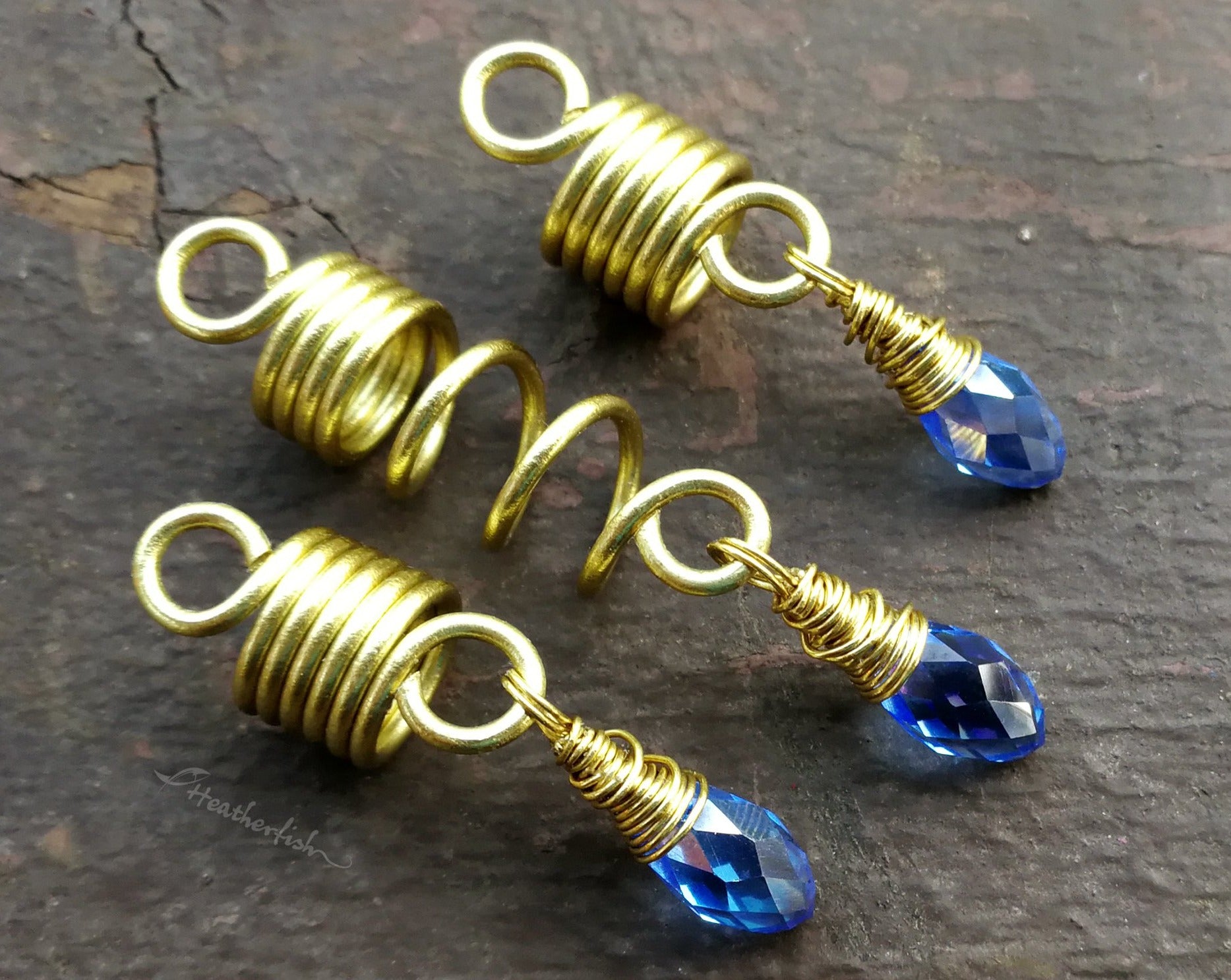 Top view of a Set of 3 dread beads with periwinkle glass accents on a painted wood background.