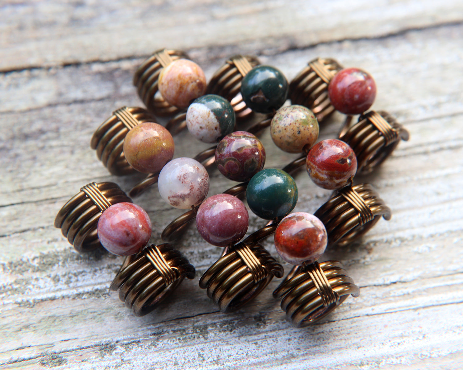 Set of 5 jasper dread beads on white washed wood background.