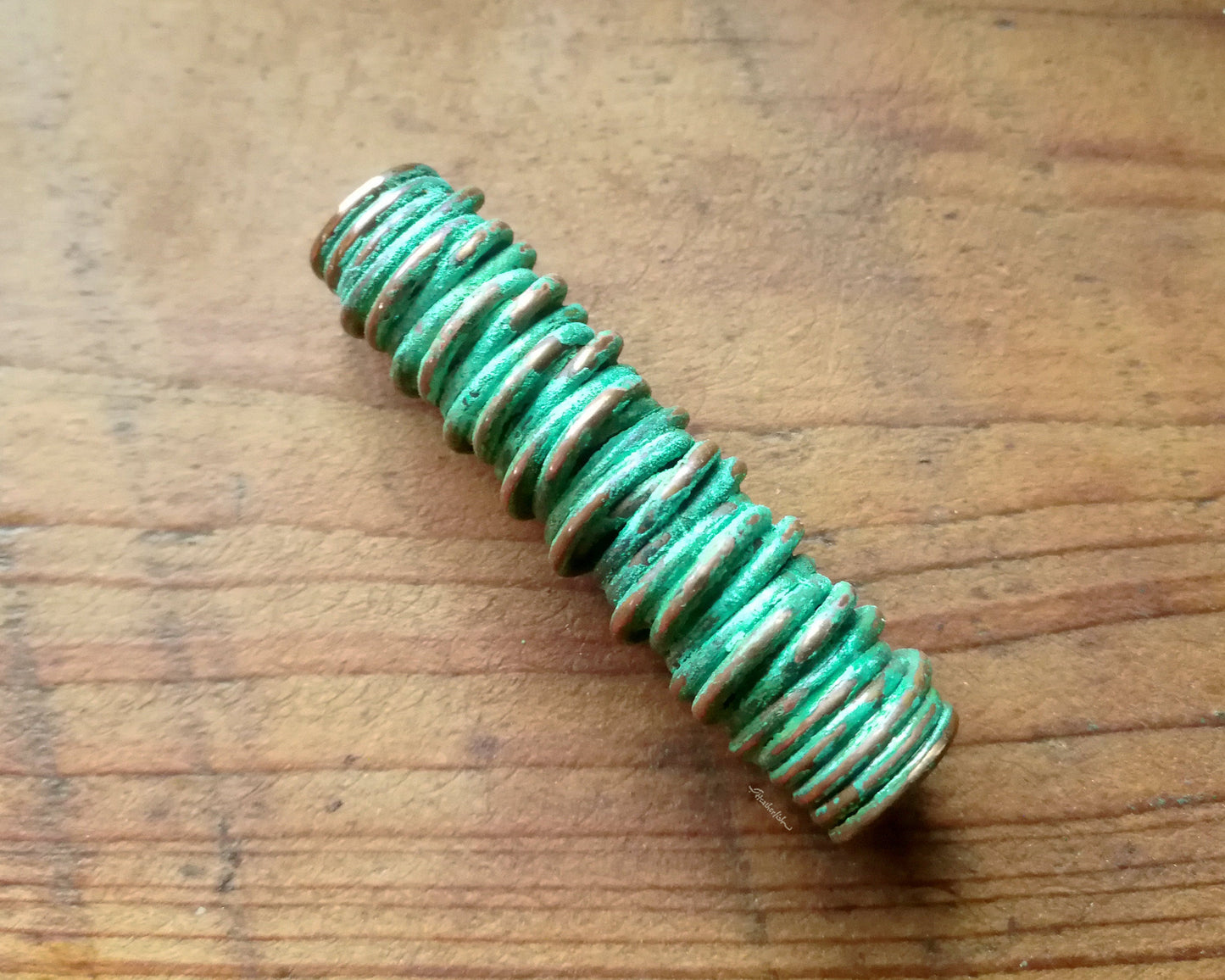 A top view of a Green Patina Copper Dread Bead.