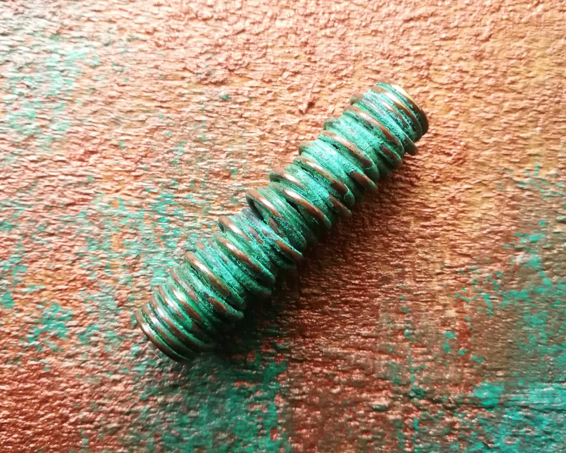 A side view of a Green Patina Copper Dread Bead.
