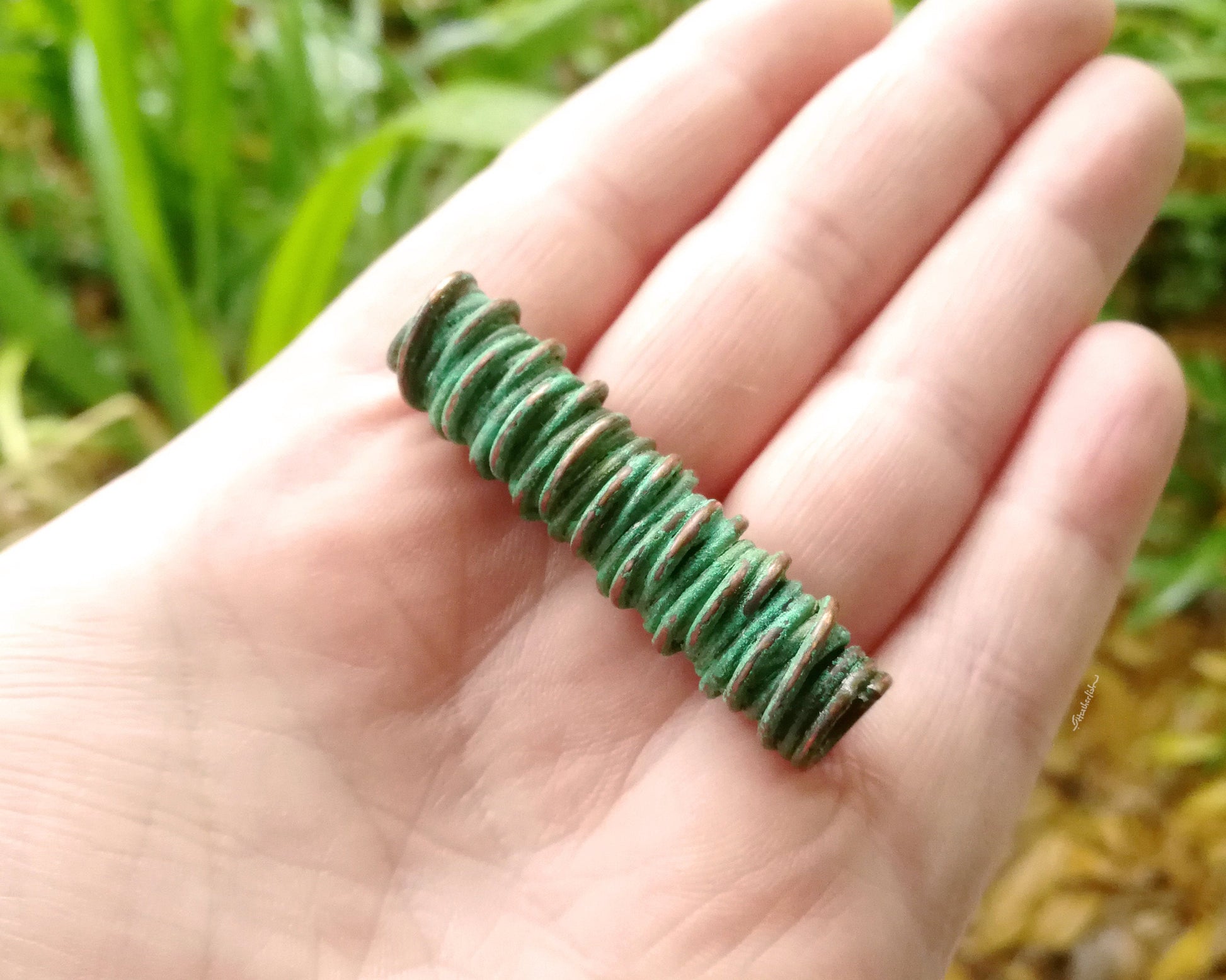 A top view of a Green Patina Copper Dread Bead in hand.