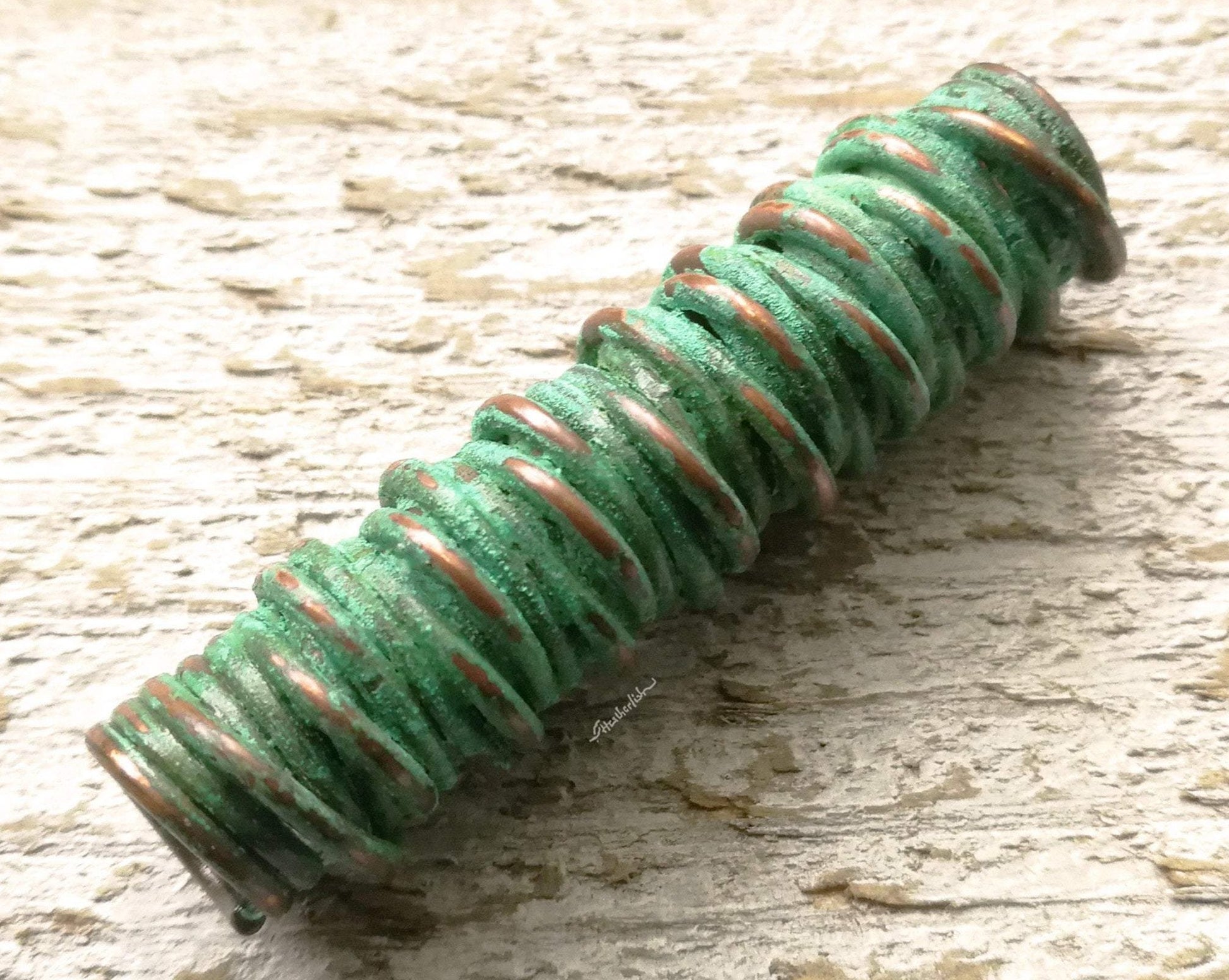 A close up view of a Green Patina Copper Dread Bead.