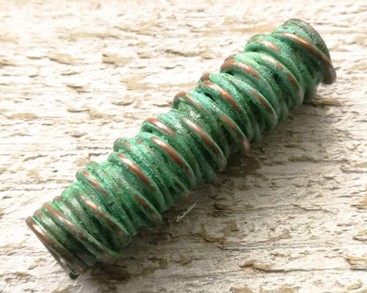 A close up view of a Green Patina Copper Dread Bead.