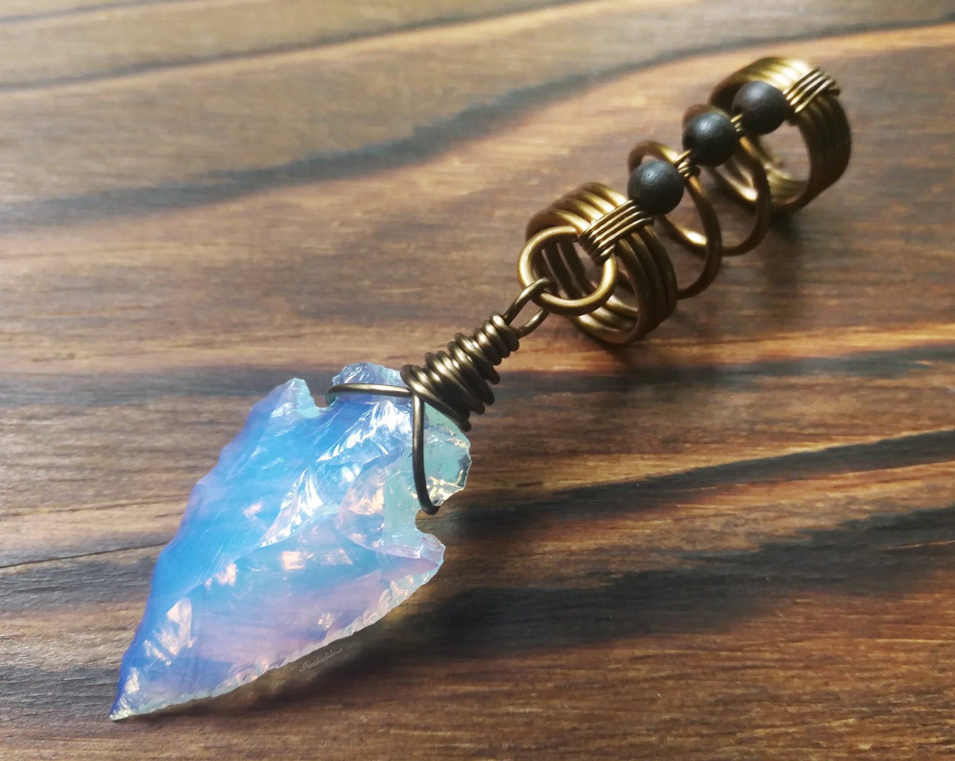 A side view of a Opalite Glass Arrowhead Dread Bead.