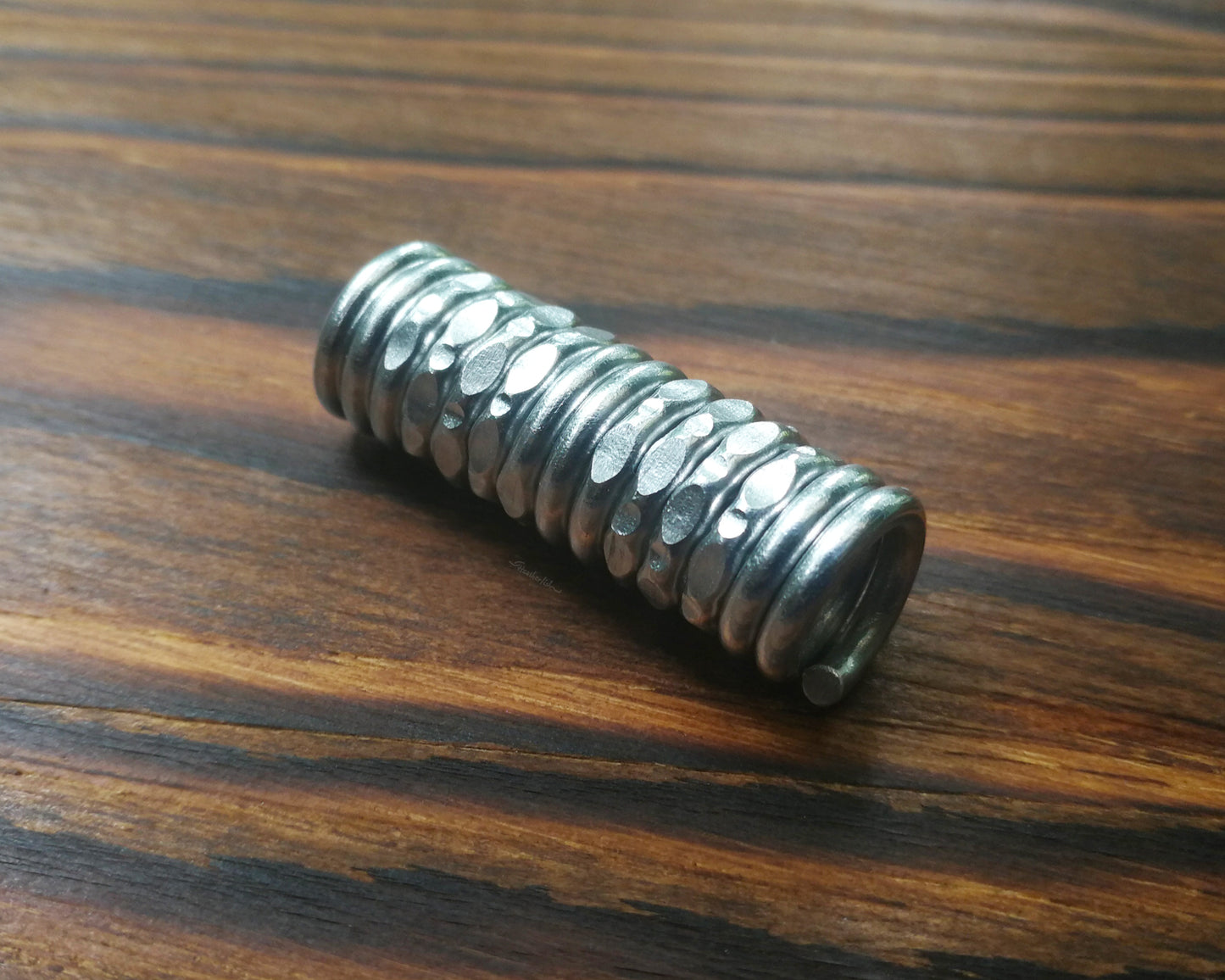 A textured dread bead displayed on wood