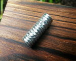 Top view of a textured dread bead on wood background