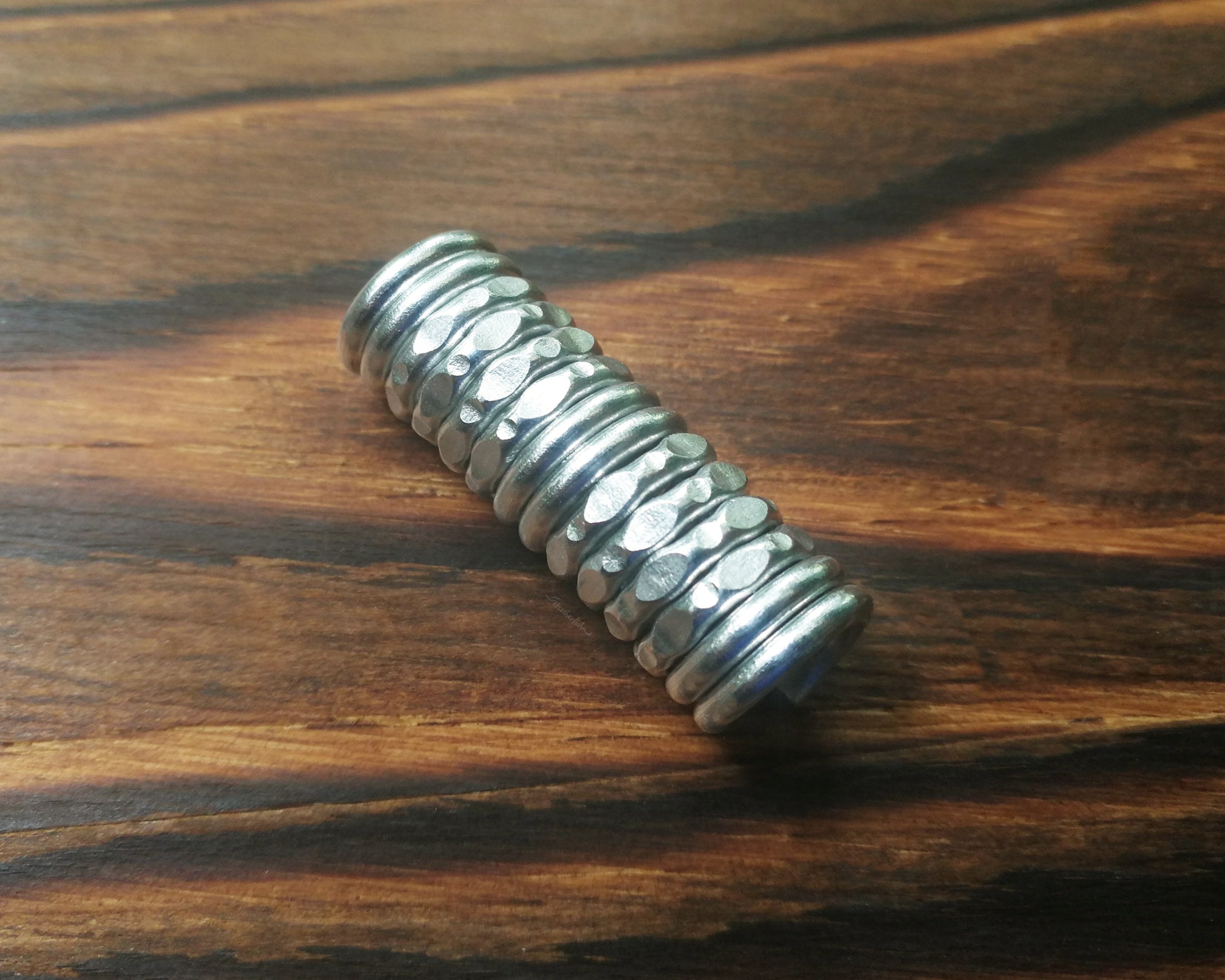 Top view of a textured dread bead on wood background