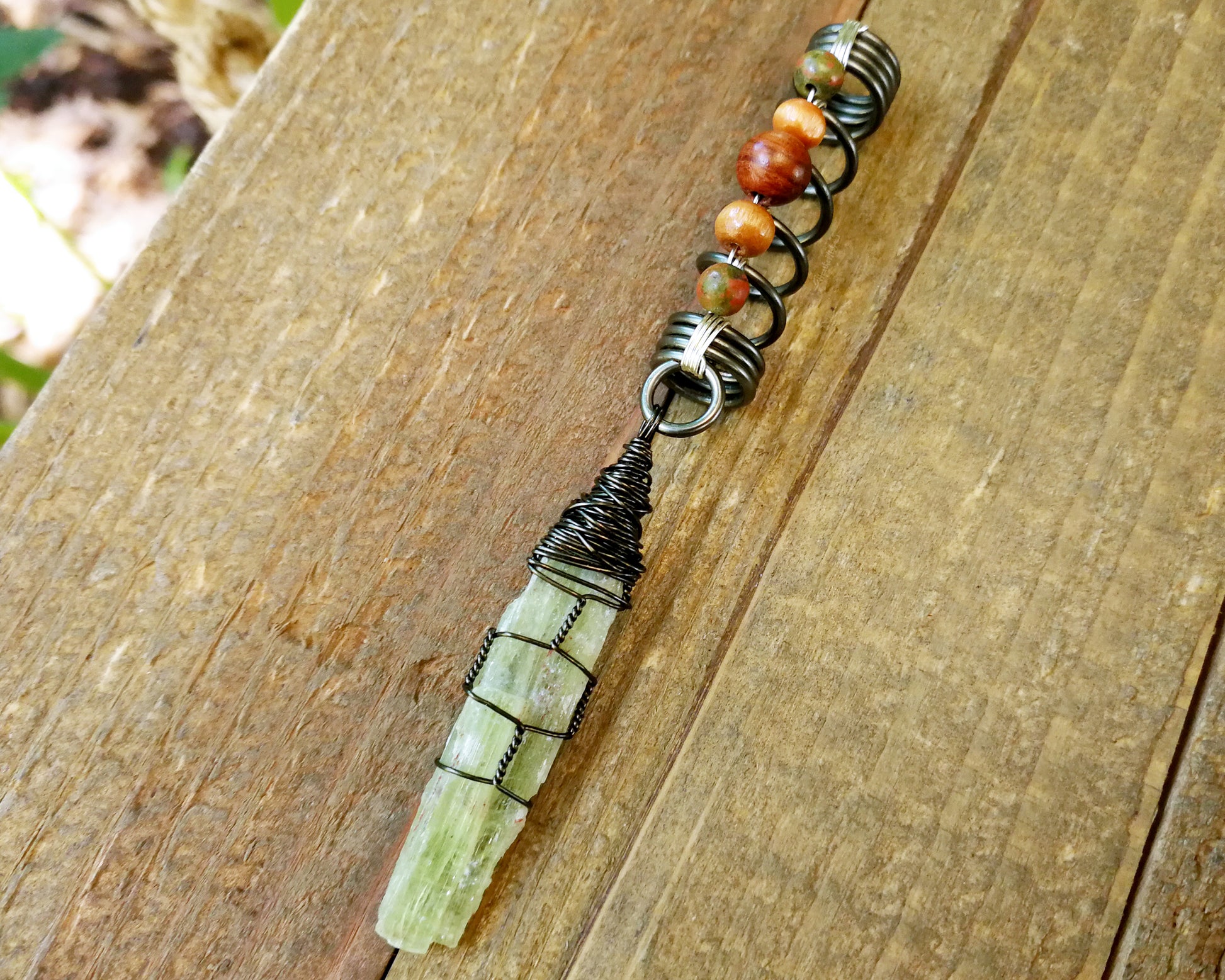 Green Kyanite, Hematite Dread Bead on wood background.