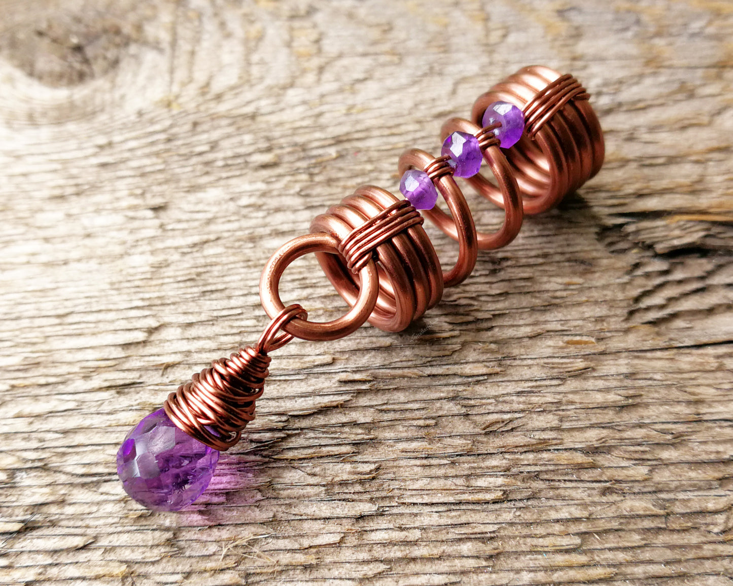 An amethyst dread bead on a wood background.