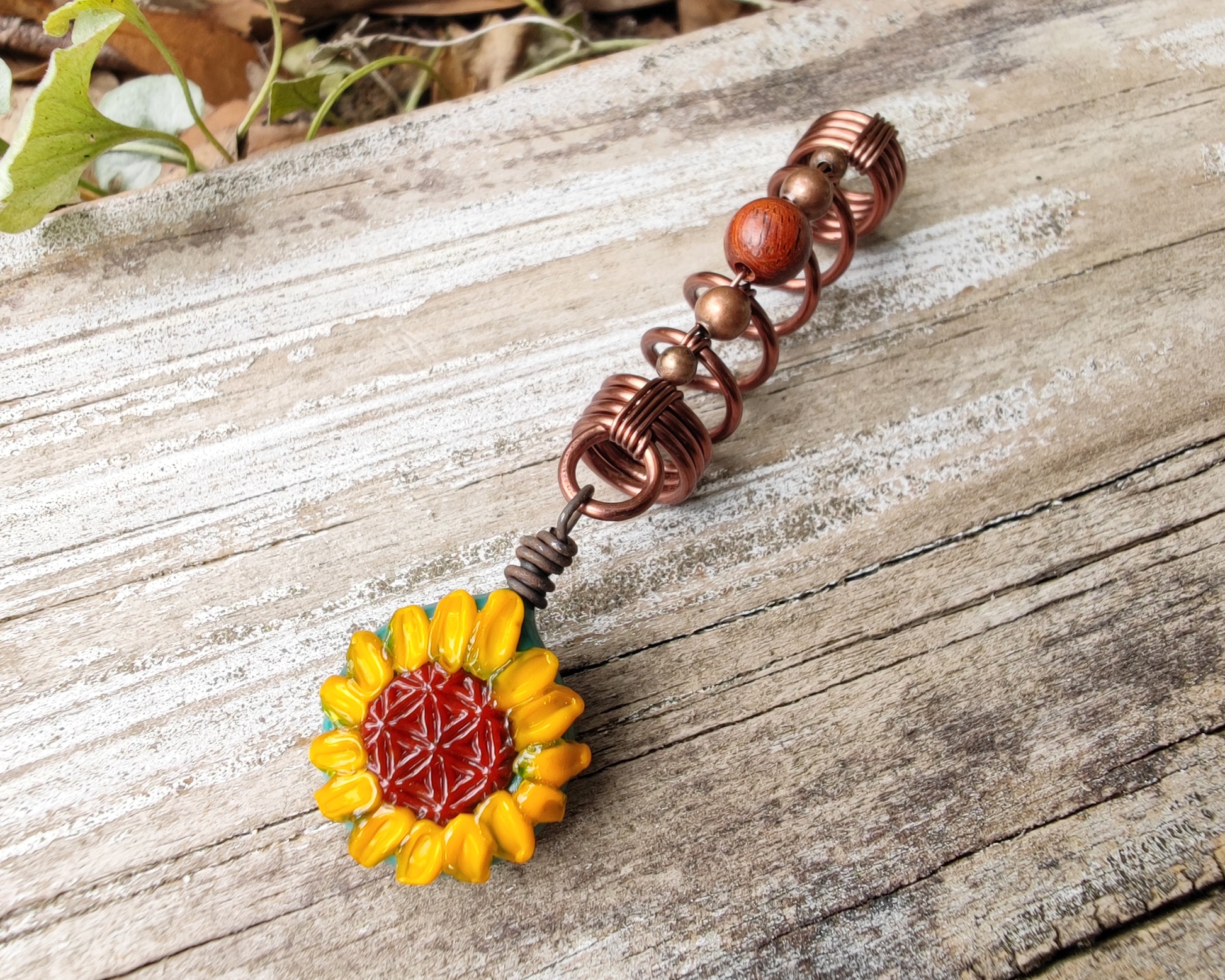 Glass Sunflower Dread Bead on a wood background.