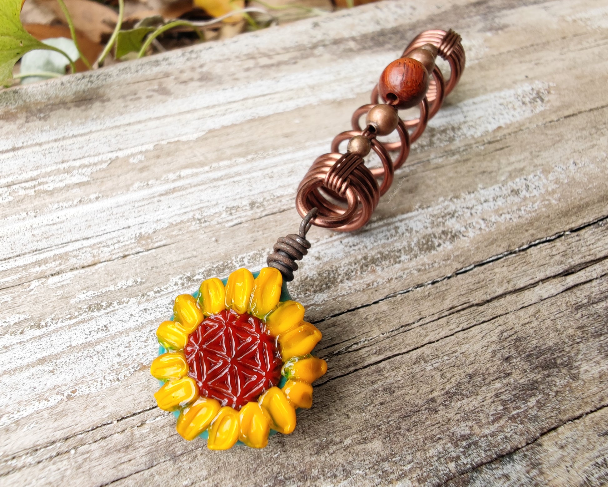 Glass Sunflower Dread Bead on a wood background.