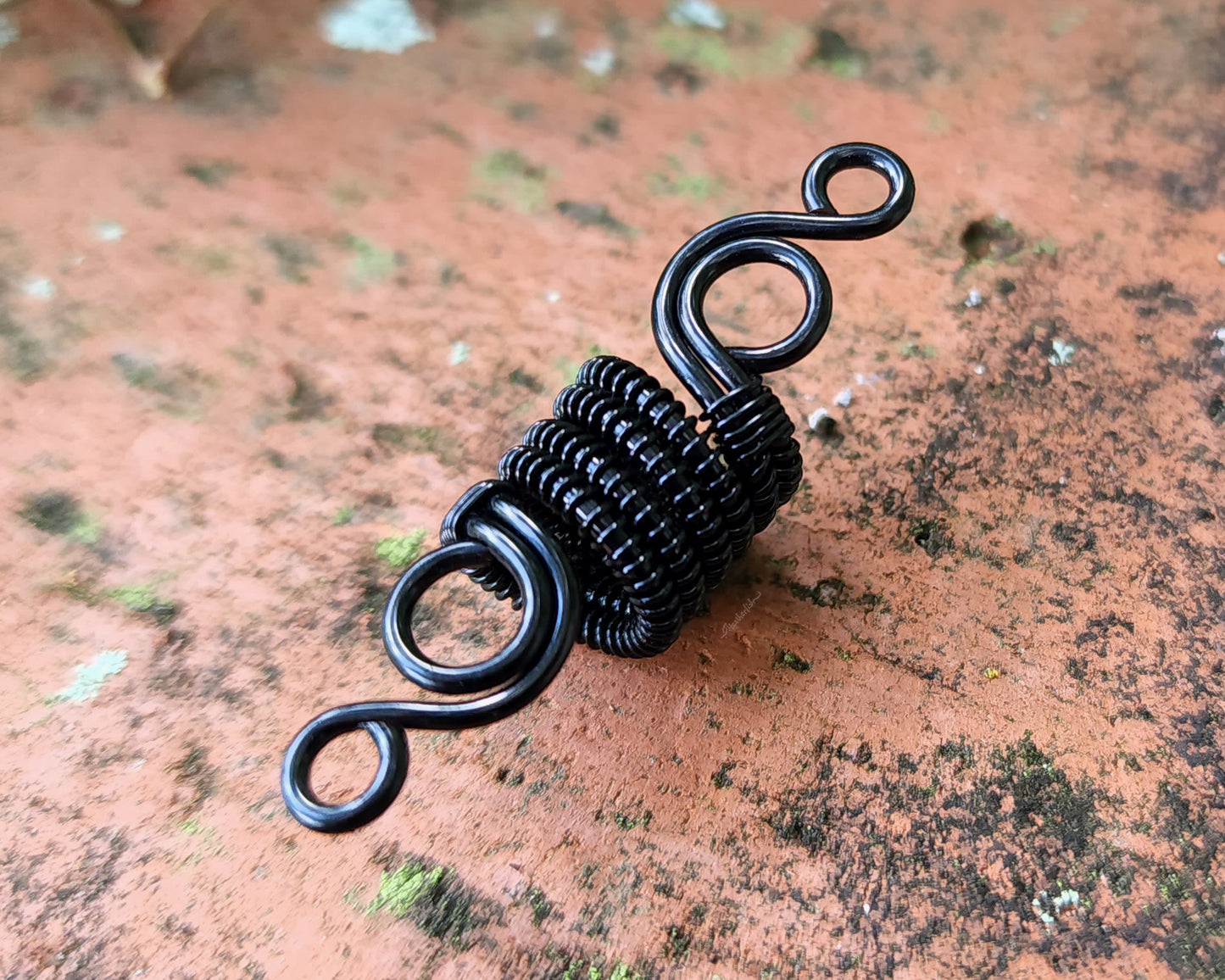 Woven Filigree Dread Bead on brick backgound.