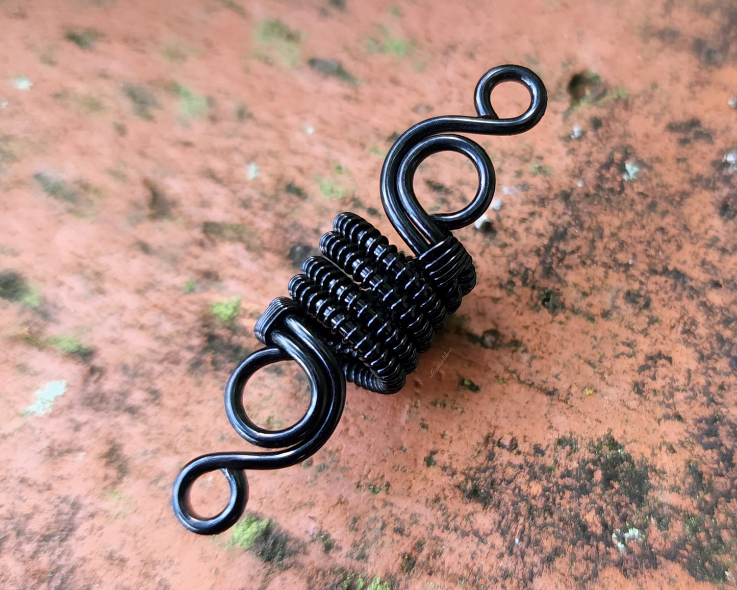 Woven Filigree Dread Bead on brick backgound.