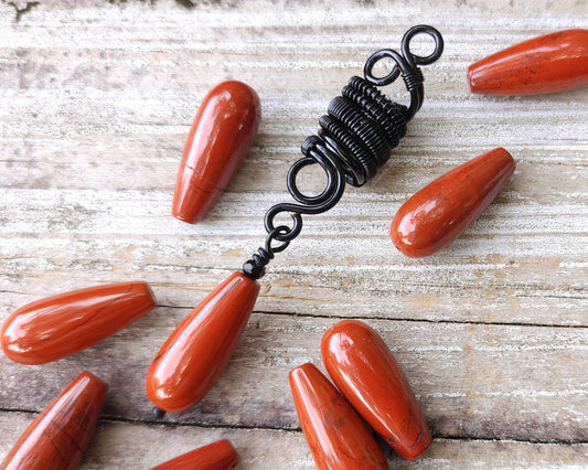 Red Jasper Tear Drop Loc Bead on a wood background.