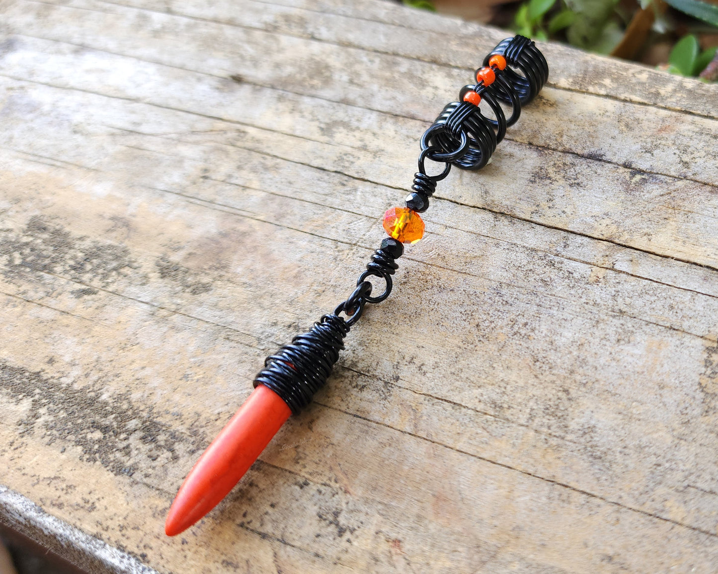 Orange Spike Loc Bead, Black Wire on wood background.