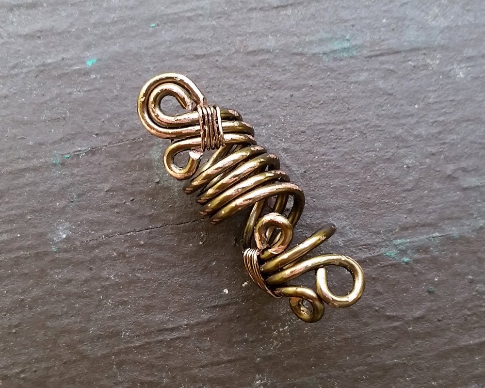 A top view of a Rustic Filigree Dread Bead on a wooden background.