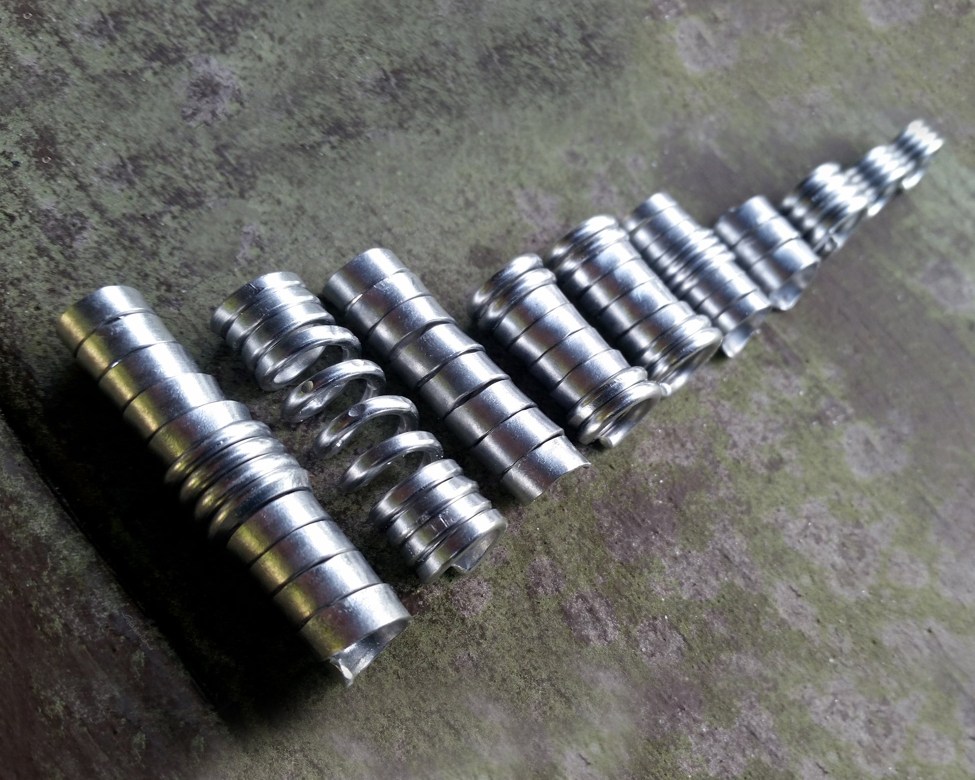 Set of 10 stylized aluminum dread beads laid out in a row