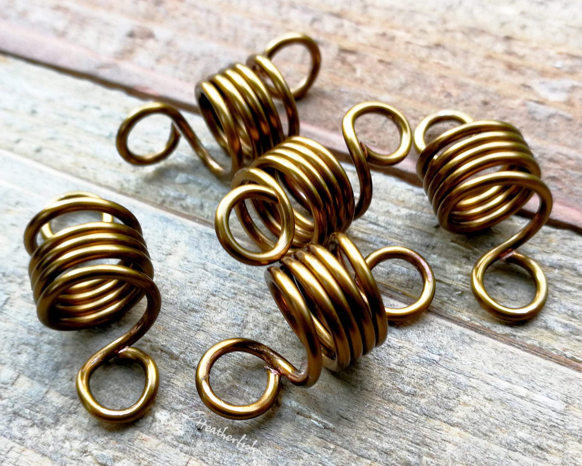 A set of 5 hair beads on a wood background.