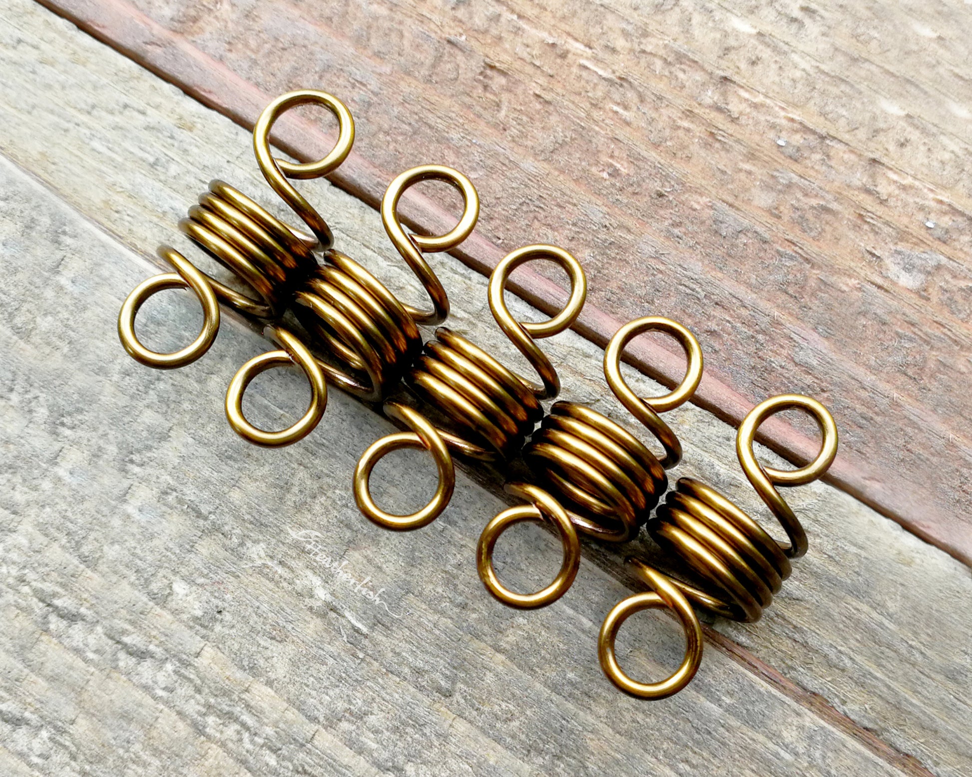 A set of 5 hair beads on a wood background.