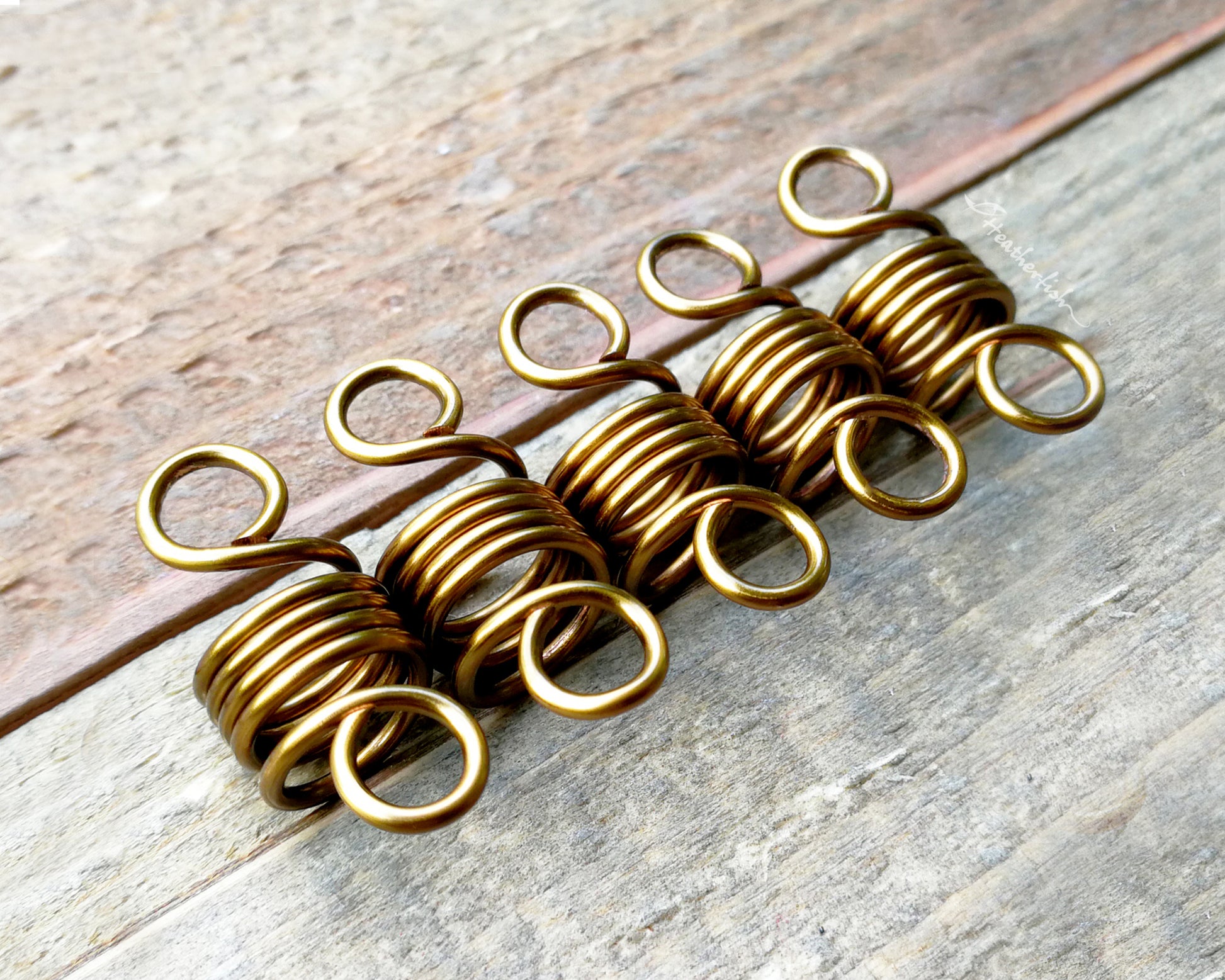 A set of 5 hair beads on a wood background.