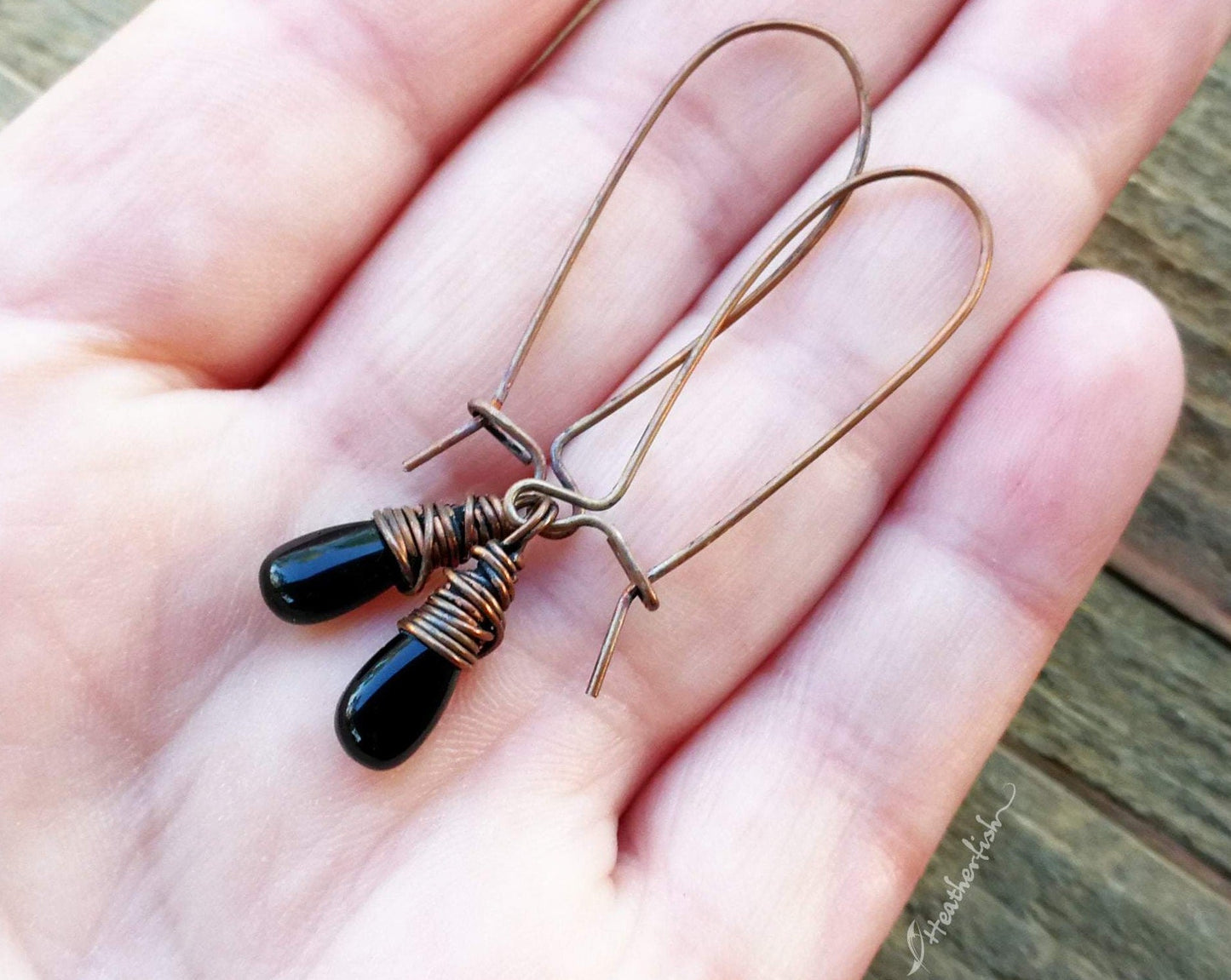 A pair of Black Onyx Earrings in hand.