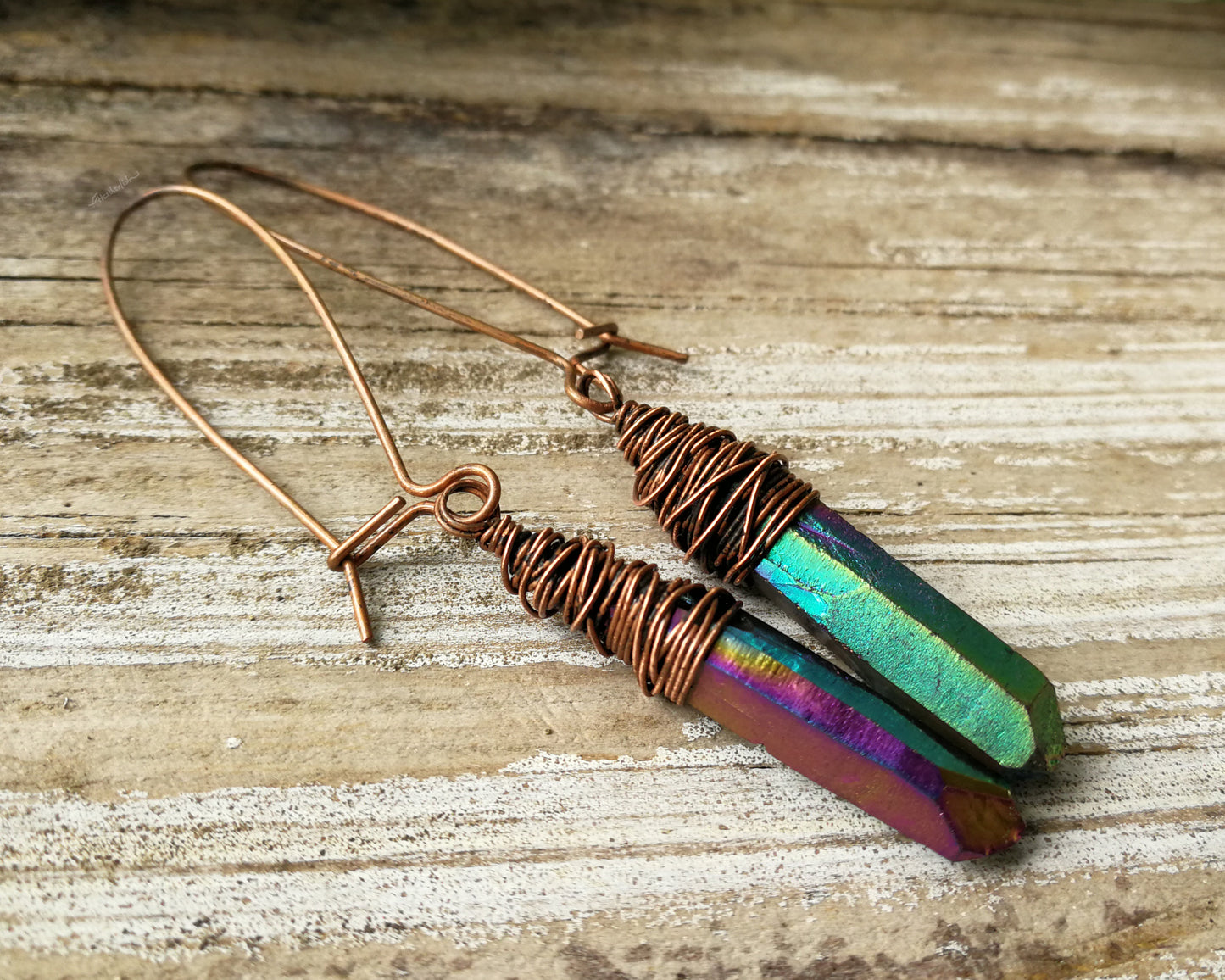 Rainbow titanium quartz earrings on a wood background.