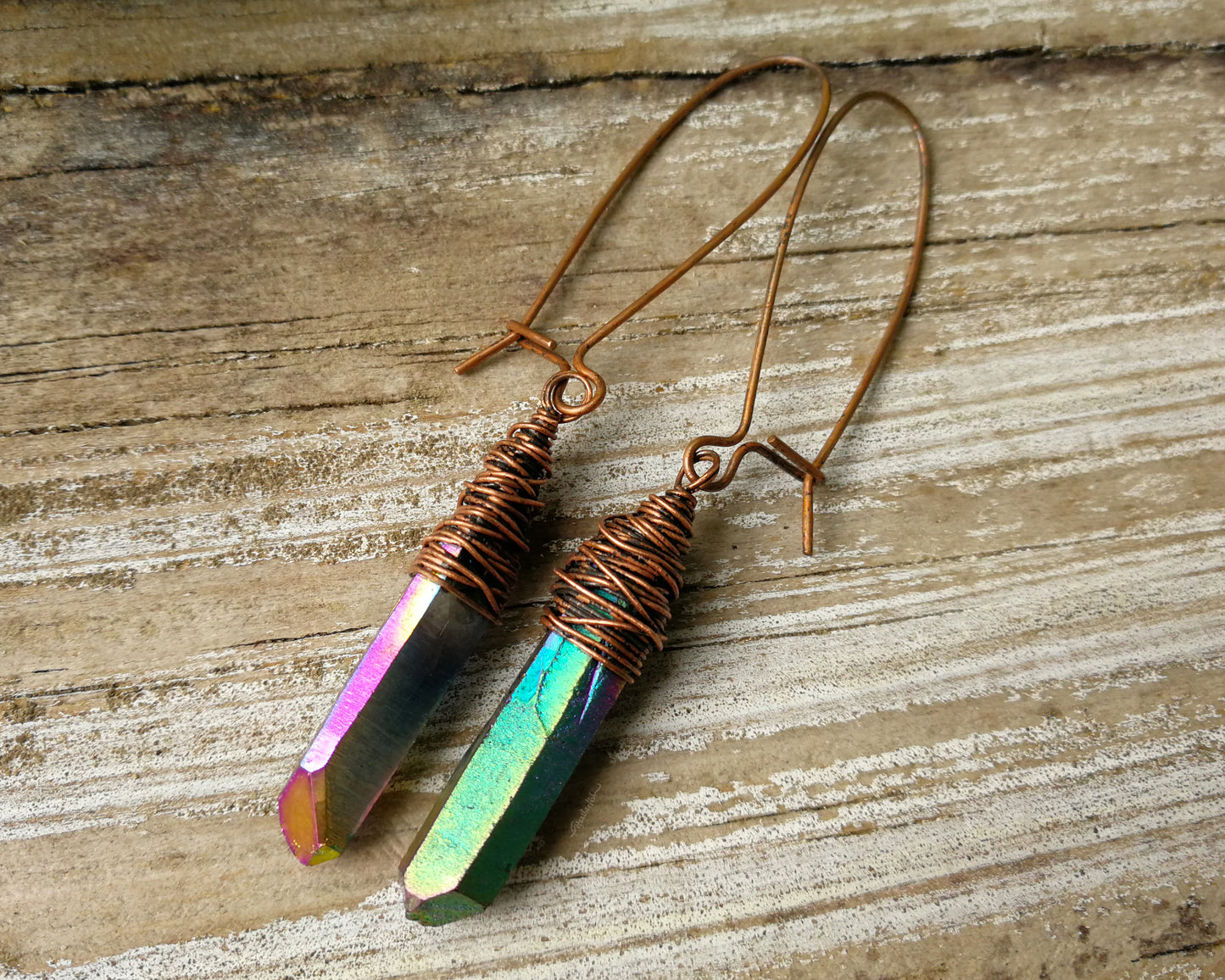 Rainbow titanium quartz earrings on a wood background.
