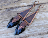 Obsidian Arrowhead Copper Earrings on a wood background.