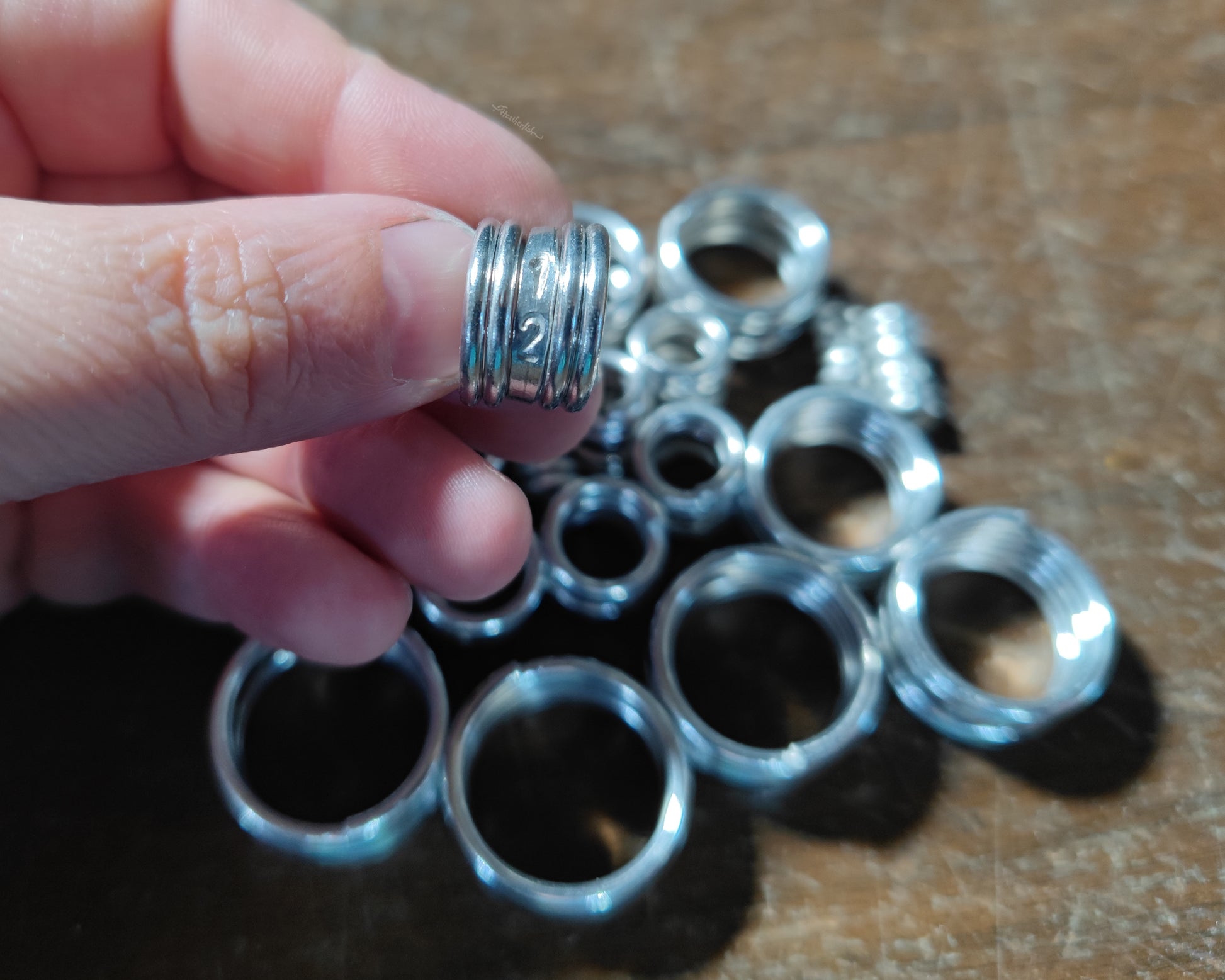 Measurement sample coils on wood background with one held in hand.