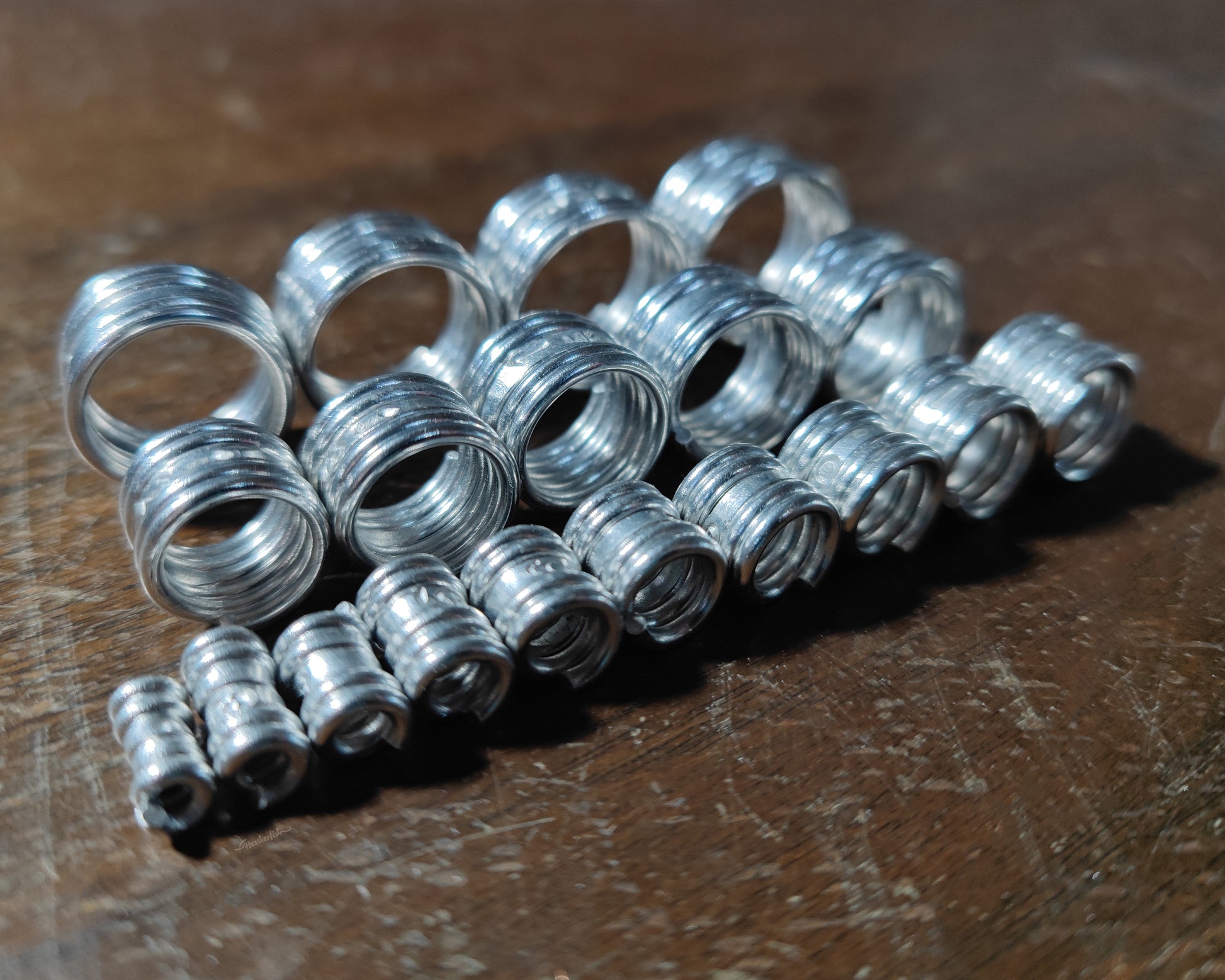 Measurement sample coils in 3 rows from 2mm through 20mm on a wood background.