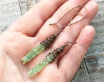 A top view of Green Kyanite Earrings wrapped in Oxidized Copper in hand.