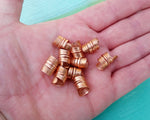 A top view of Stylized Copper Dread Beads Set of 10 in hand.