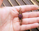 A top view of a Purple Czech Dread Bead in hand.