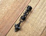 A top view of a Shark Tooth Dread Bead with Black Lava Beads.