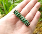 A top view of a Green Patina Copper Dread Bead in hand. 