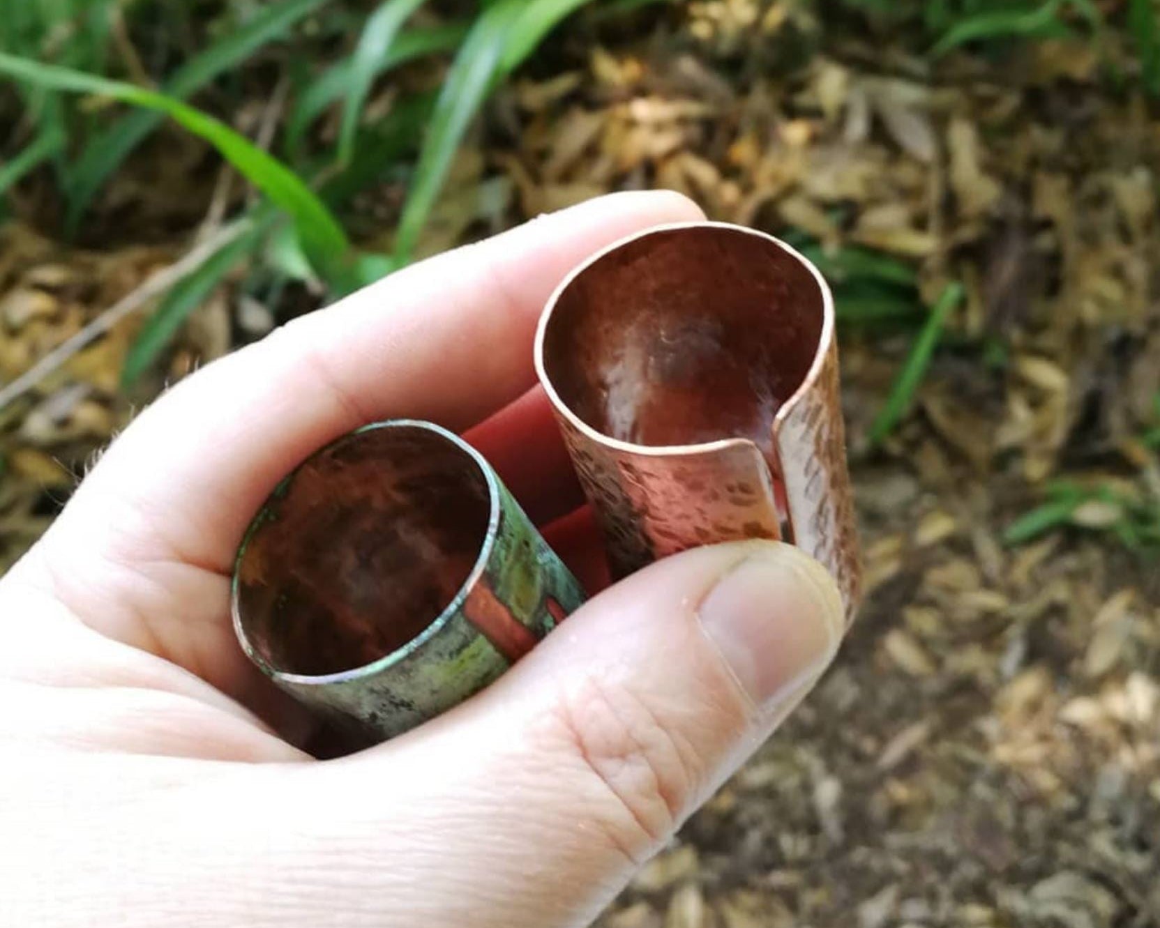 Two copper hair cuffs held in hand to show scale.