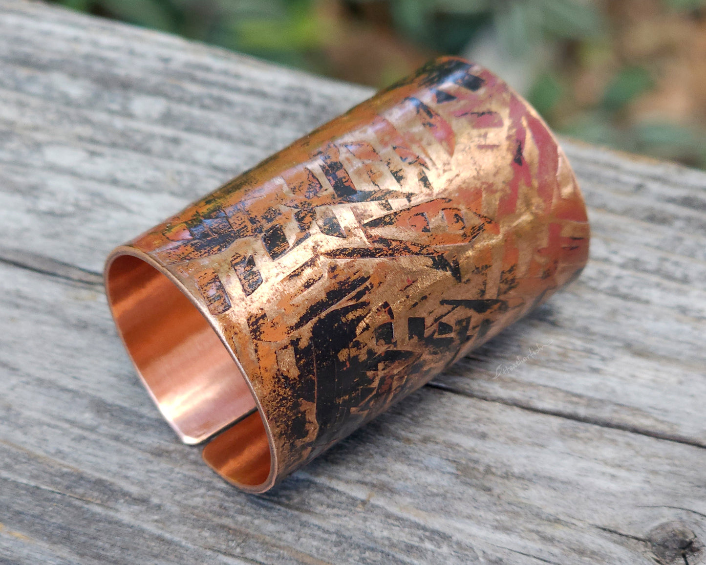 A large texturized hair cuff in copper displayed on a rustic wood board.