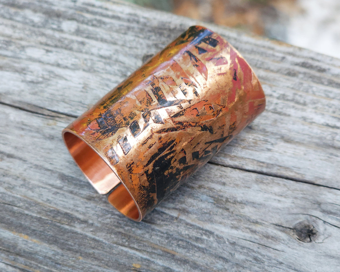 A large texturized hair cuff in copper displayed on a rustic wood board.