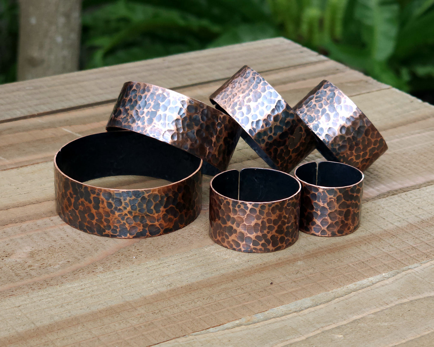 Copper hair cuffs lined up on a wood surface to show size options.