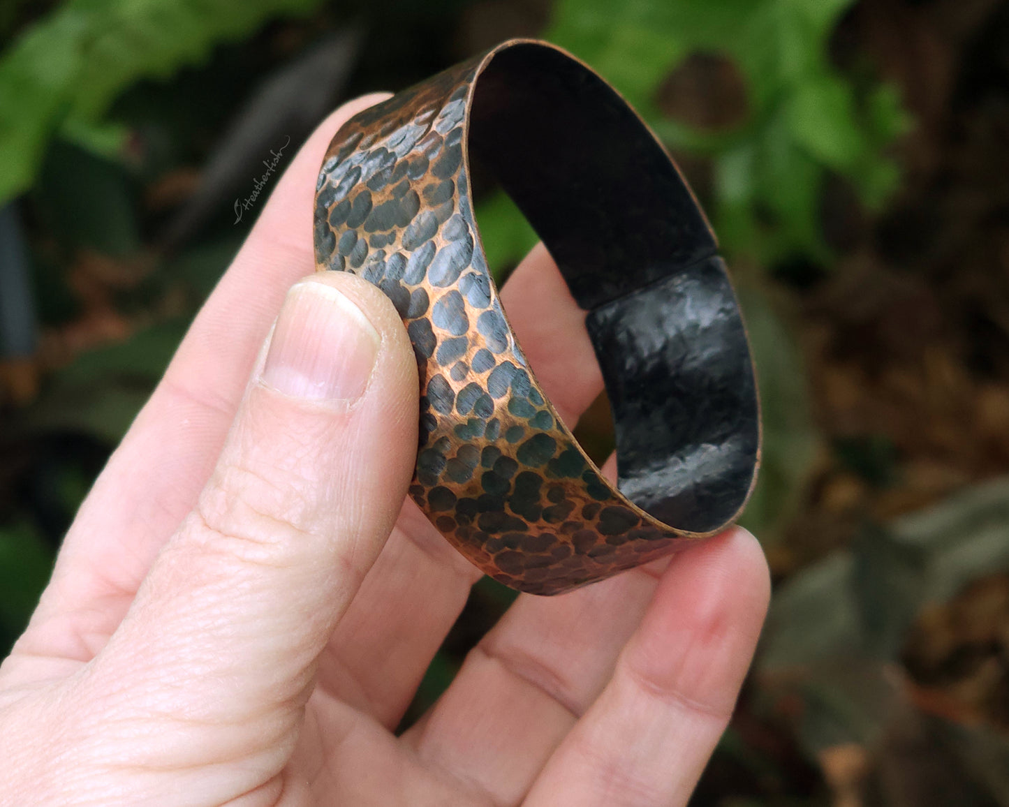 Copper hair cuff held in hand with a natural background.