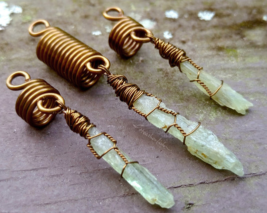 A set of 3 kyanite hair beads on a brown wood background.