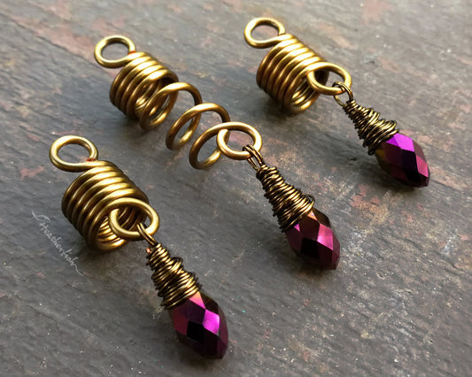 Set of 3 purple gold loc jewelry on a brown wood background.