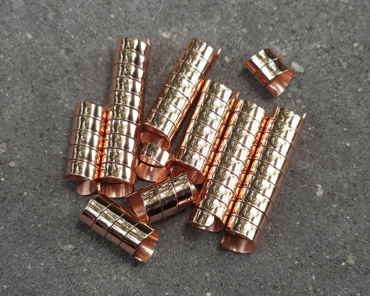 Varied length copper hair coils on a stone background.