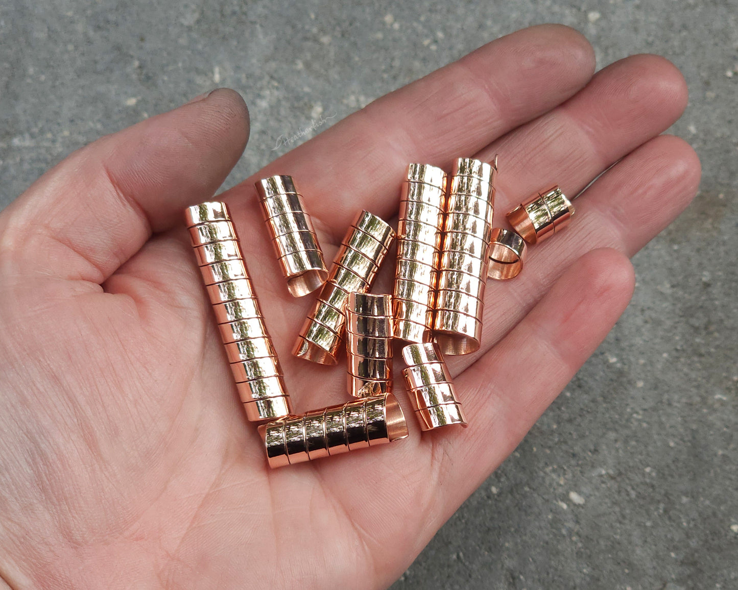 Varied length copper hair coils held in a hand with a stone background.