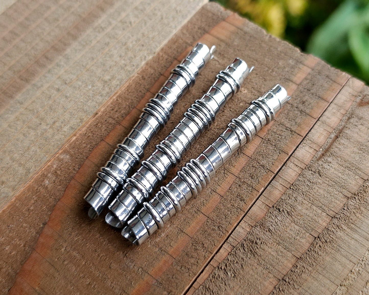 A set of 3 aluminum dread beads on a wood surface.