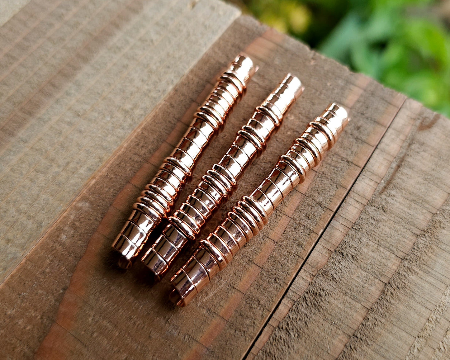 A set of copper hair coils on a wood surface.